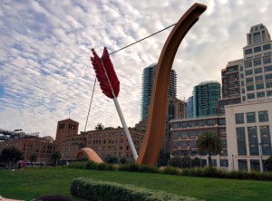 bow and arrow sculpture in front of buildings