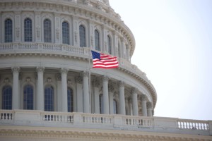 closeup of us capitol building with flag of the us flying