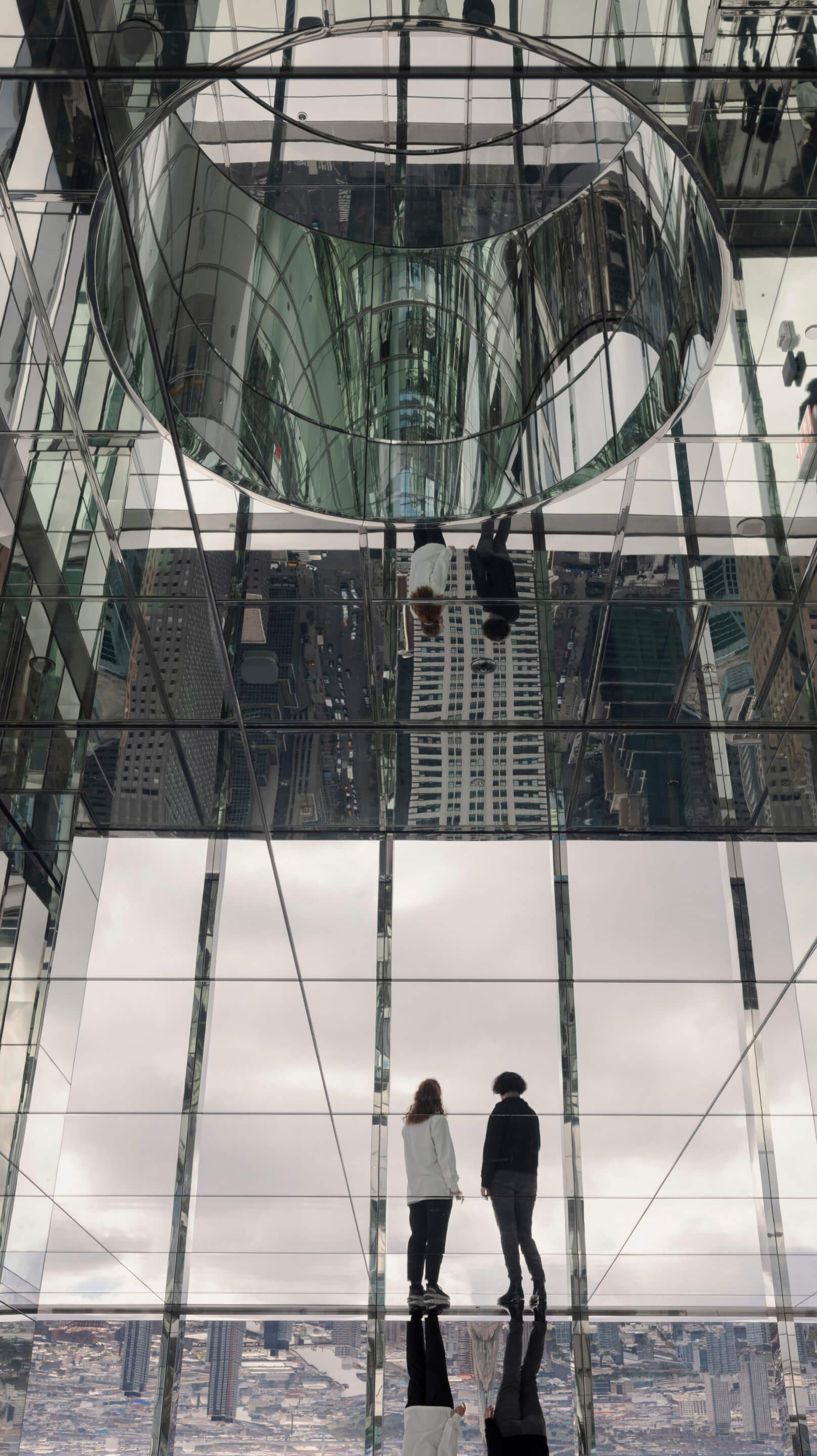people standing in a mirrored observation room in a skyscraper