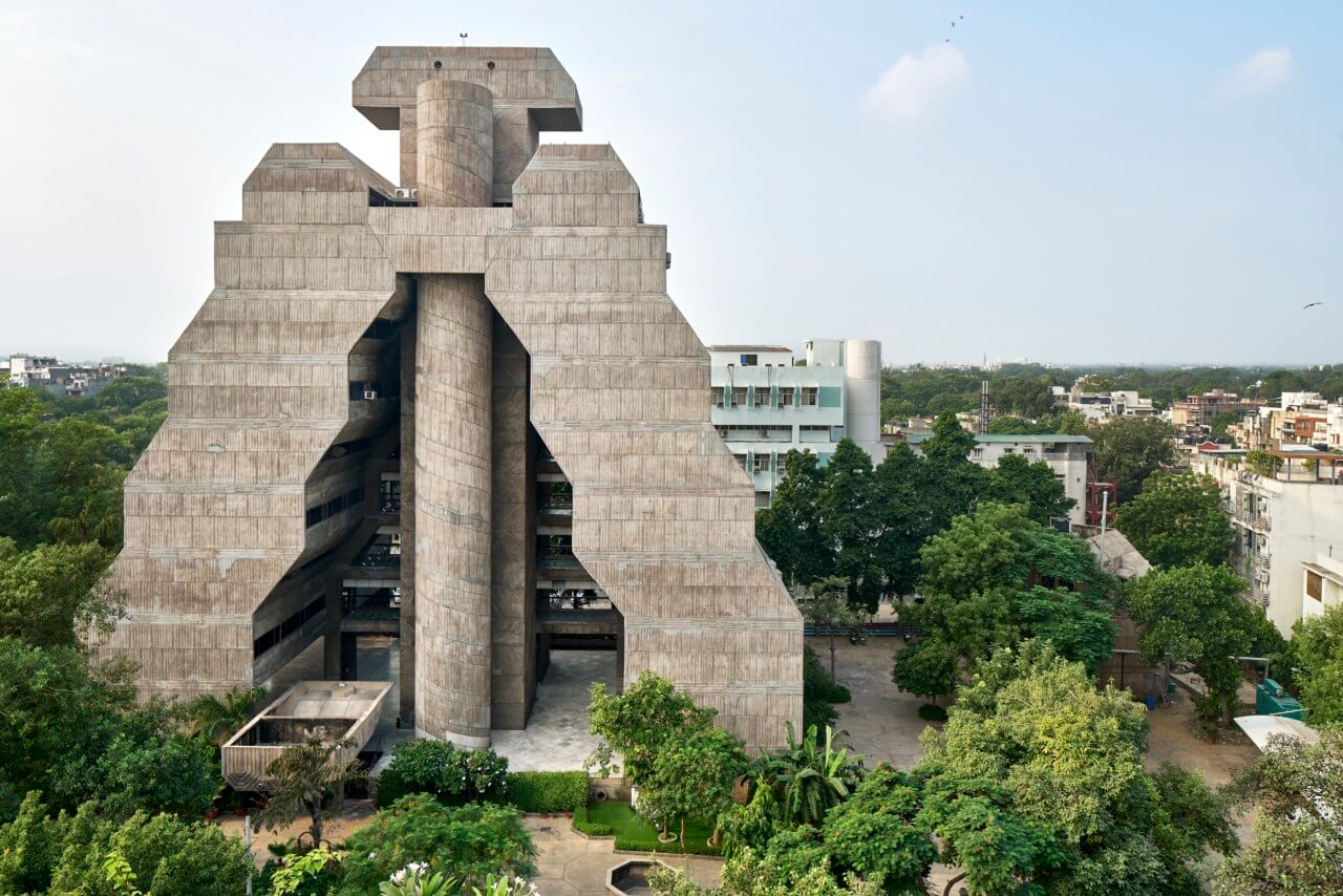 a concrete building in india surrounded by a lush landscape