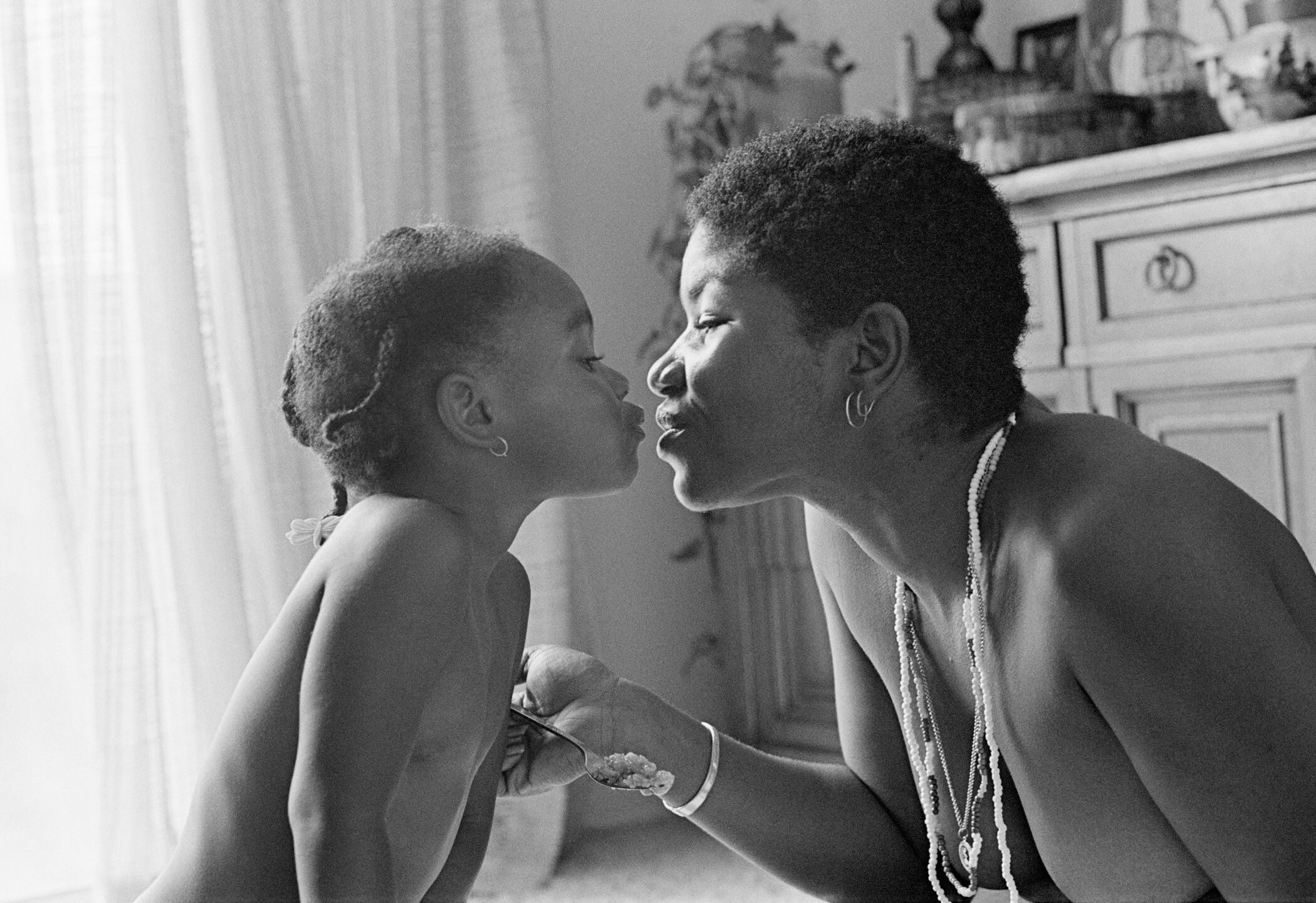 a Black mother and child sharing a kiss