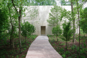 a pathway leading through trees to a concrete pavilion