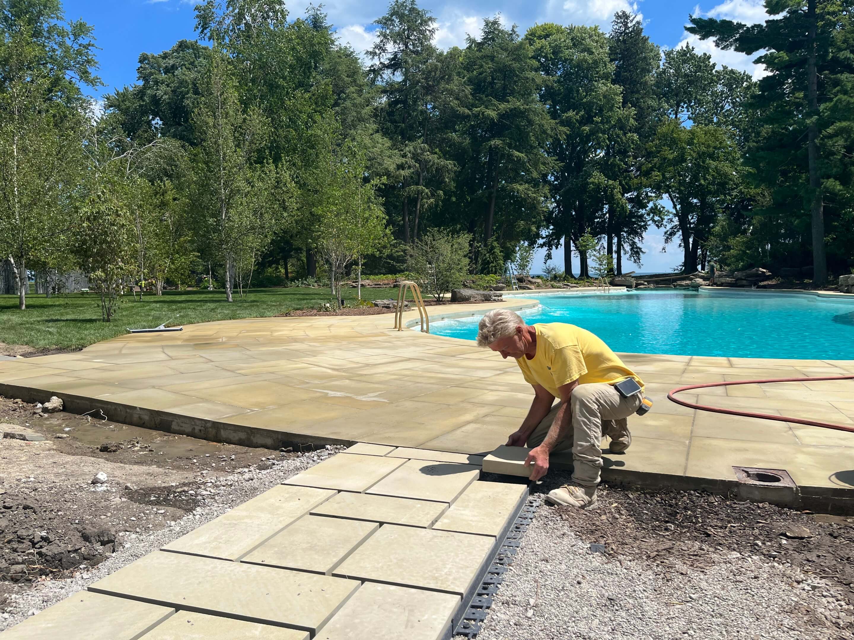a man installs pavers next to a pool