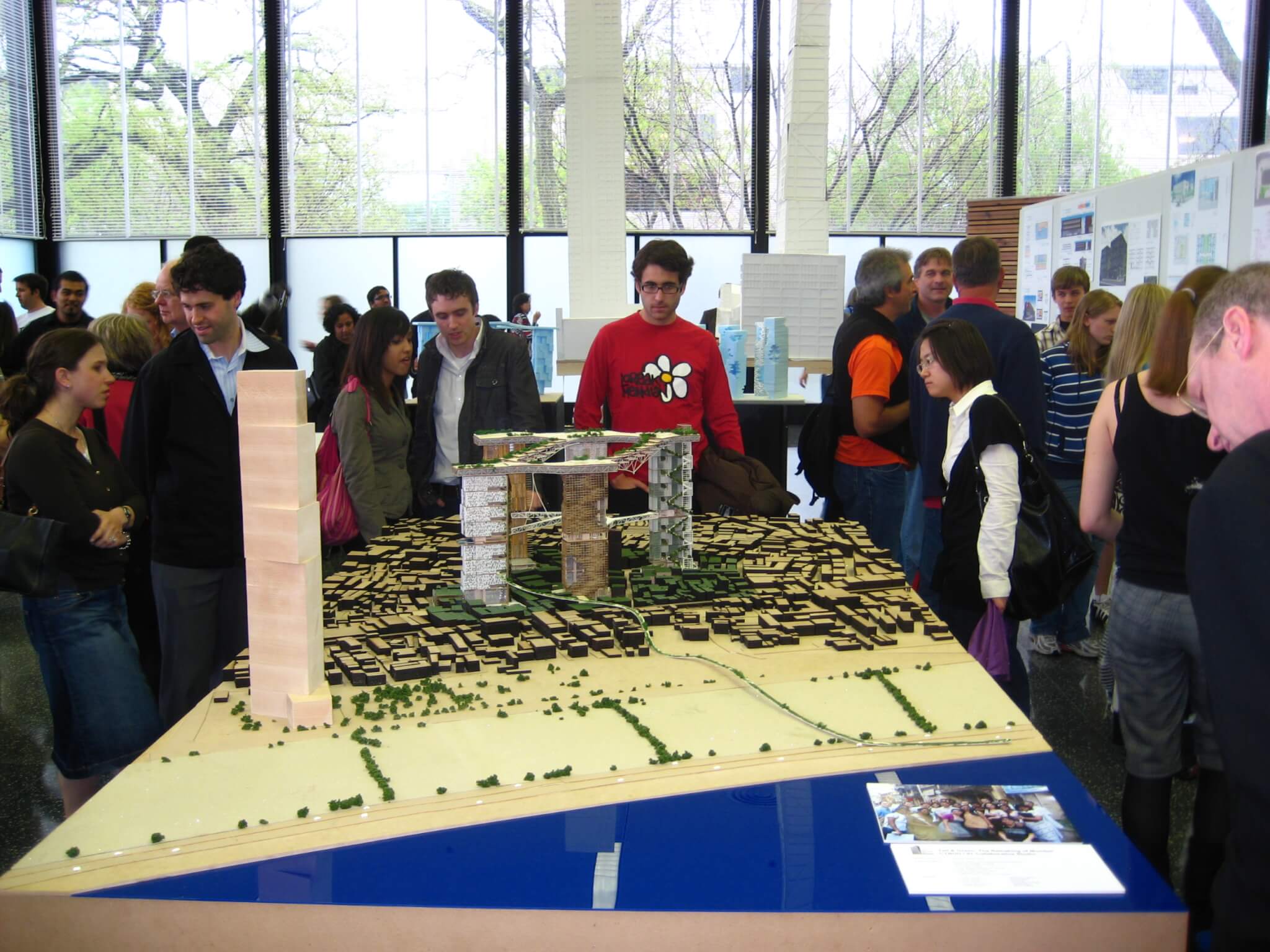 people mill around an architectural model at an exhibition