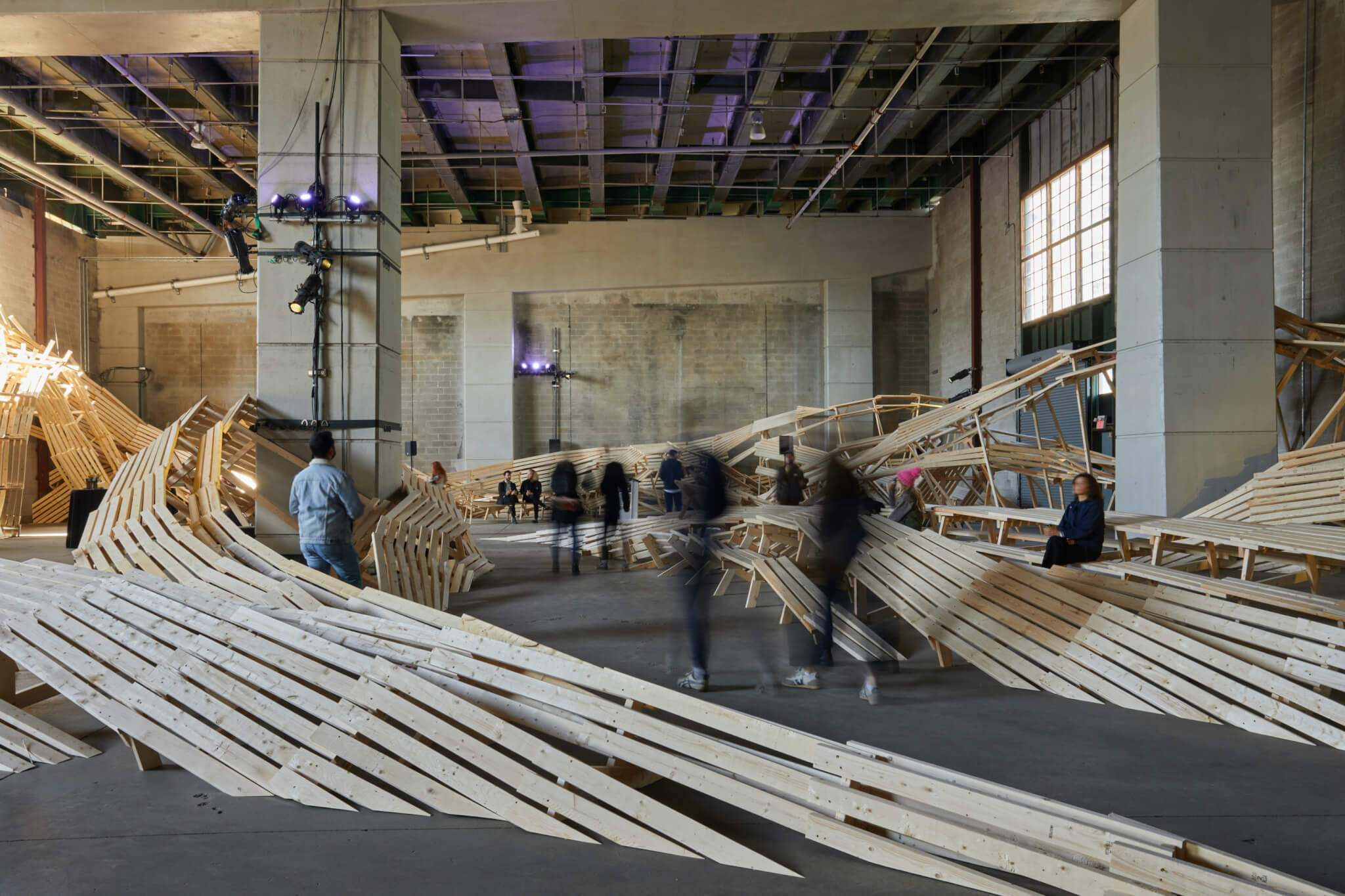 people visit an art installation with large wooden forms