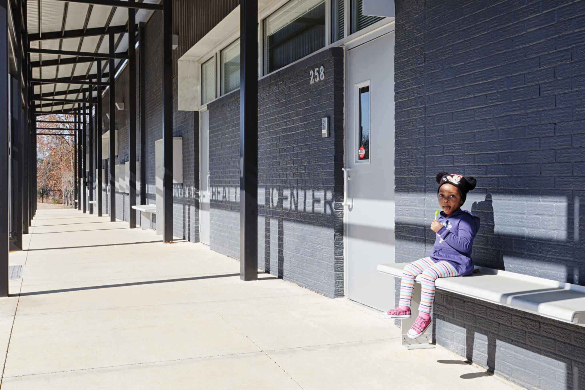 a little girl sits outside a storefront