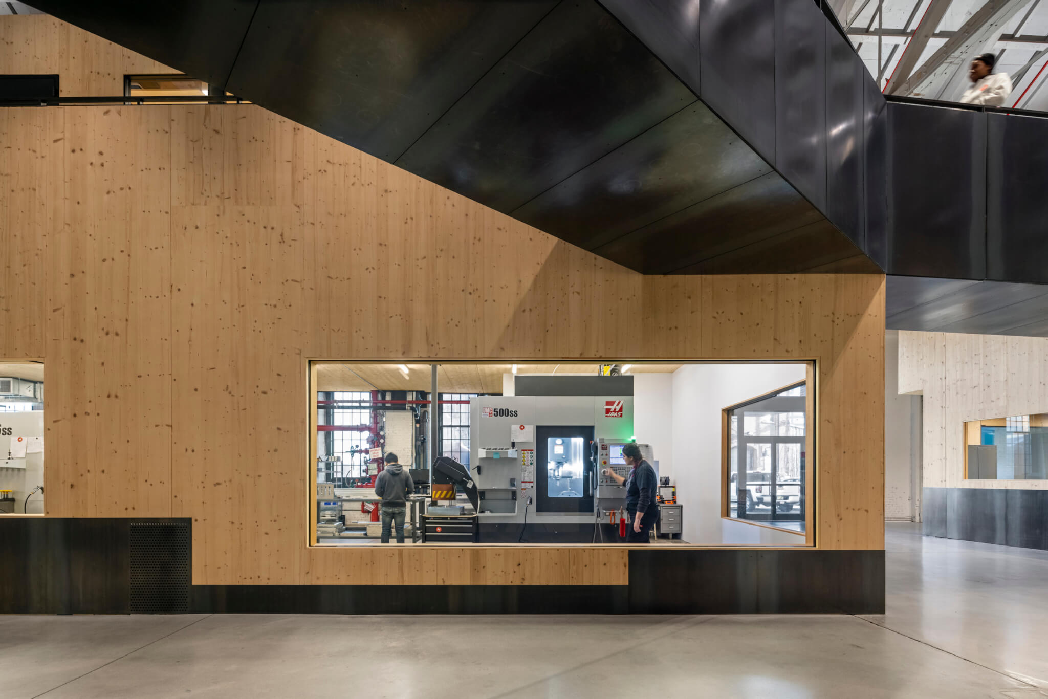 a modern factory space made up of stacked engineered wood modules and blackened steel elements