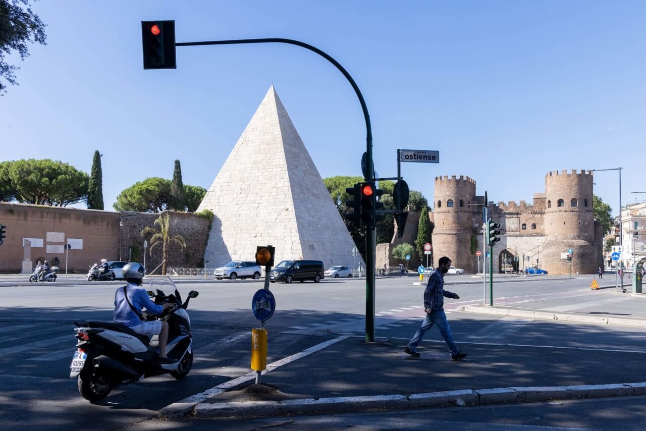 pyramid and roman ruin next to a street