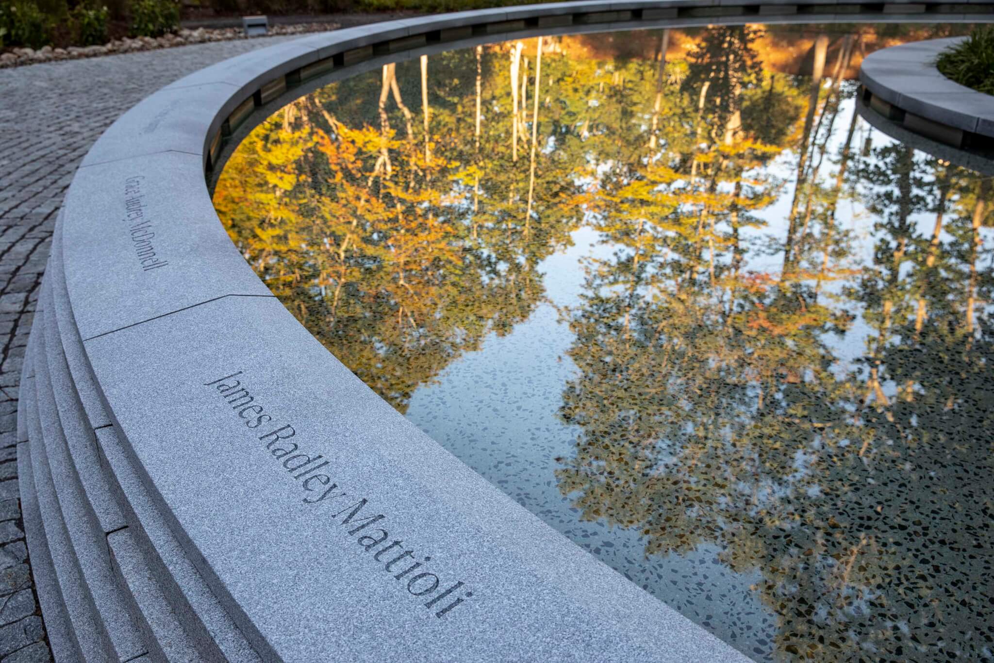Names of gun violence victims carved into a granite landscape wall