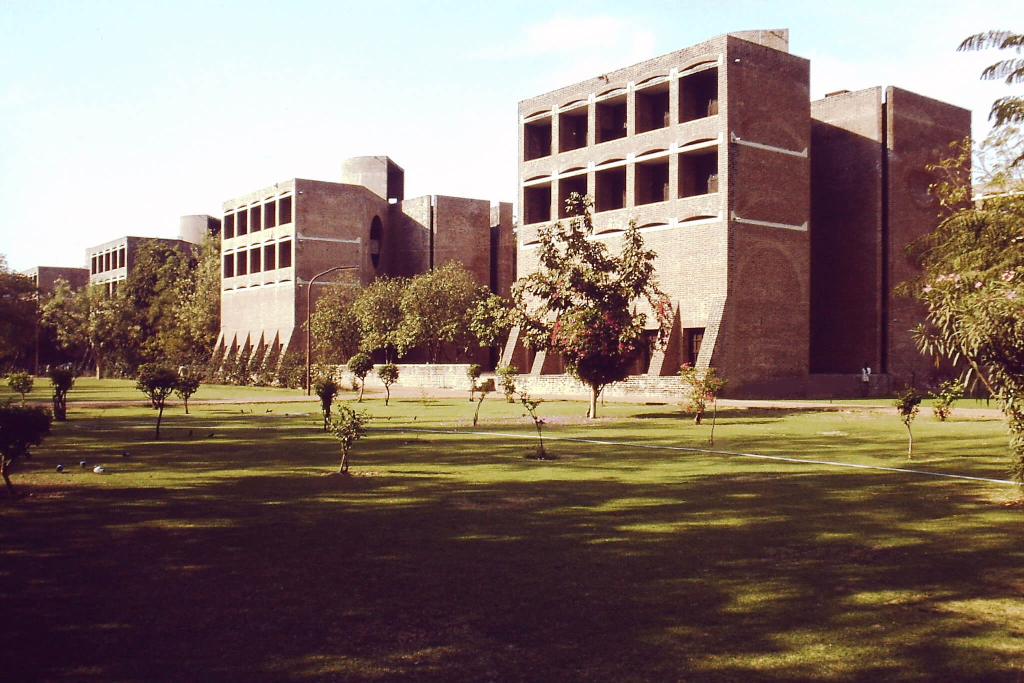 brick and concrete buildings with a lawn and trees in Ahmedabad, India