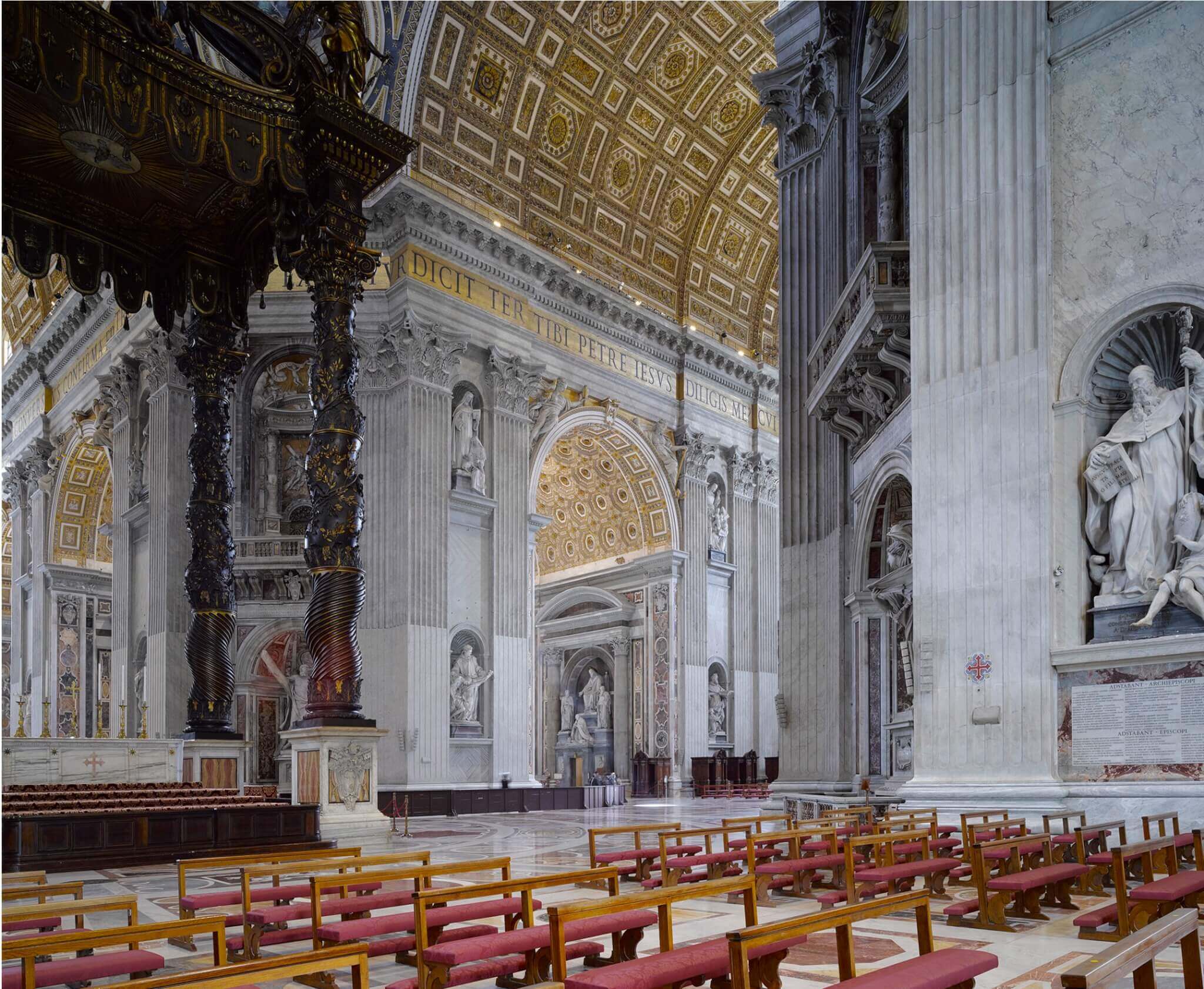 interior of Saint Peter’s Basilica with rows chairs and gold ceiling