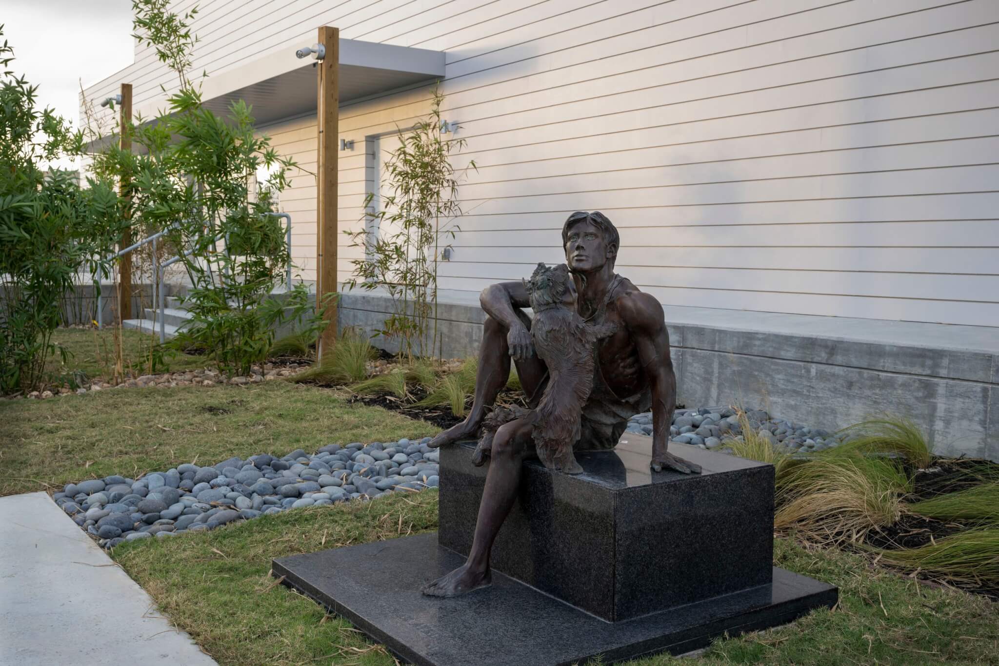 sculpture of sitting man with dog in a garden