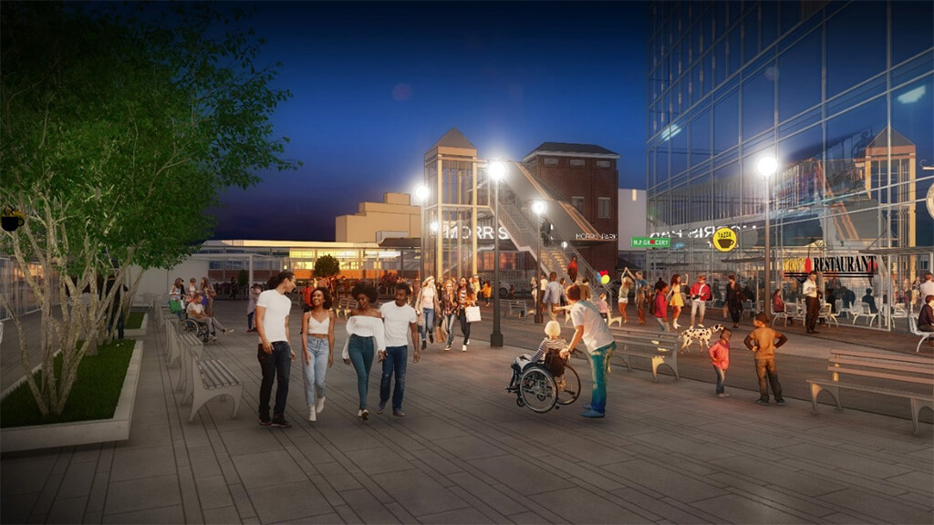 render of group walking along a paved plaza at night with at grade train station in the background