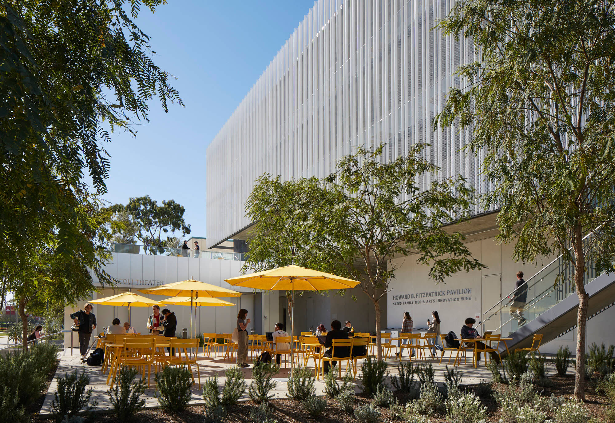 yellow umbrellas lining patio in front of new building