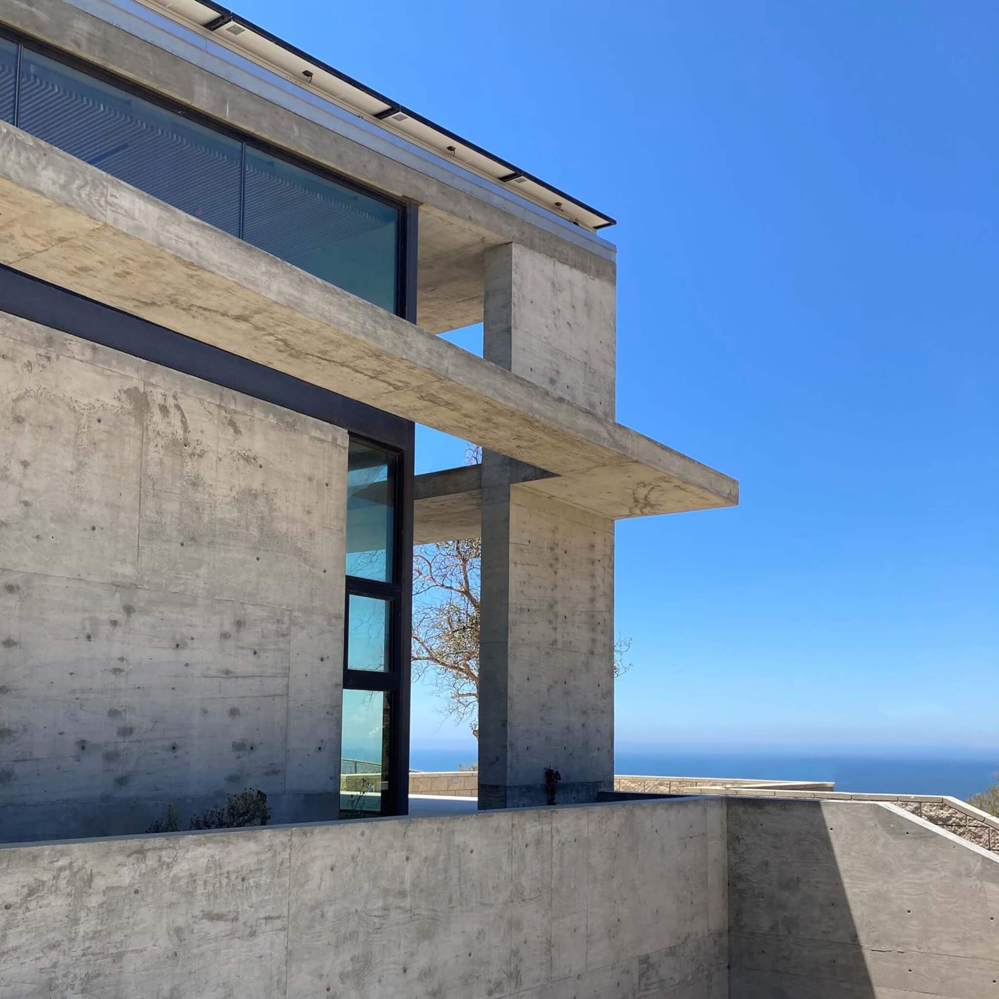 concrete house with deck overlooking blue sky and ocean