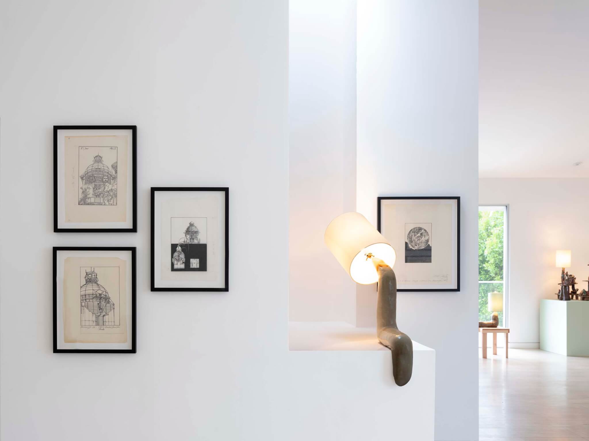 prints on white wall with sculptural lamp