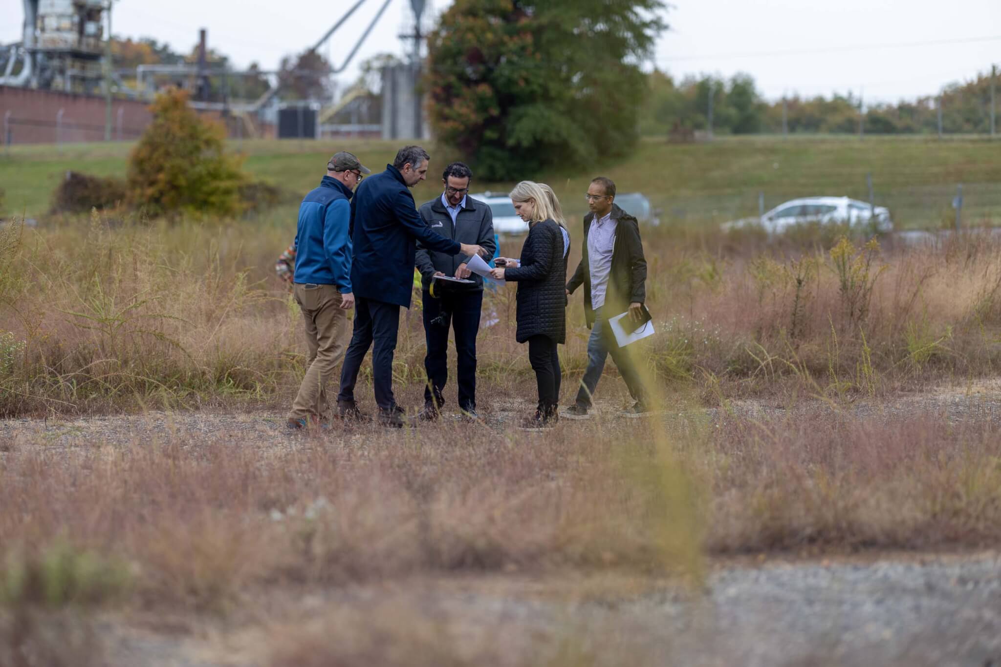 people standing on brownfield site looking at documents