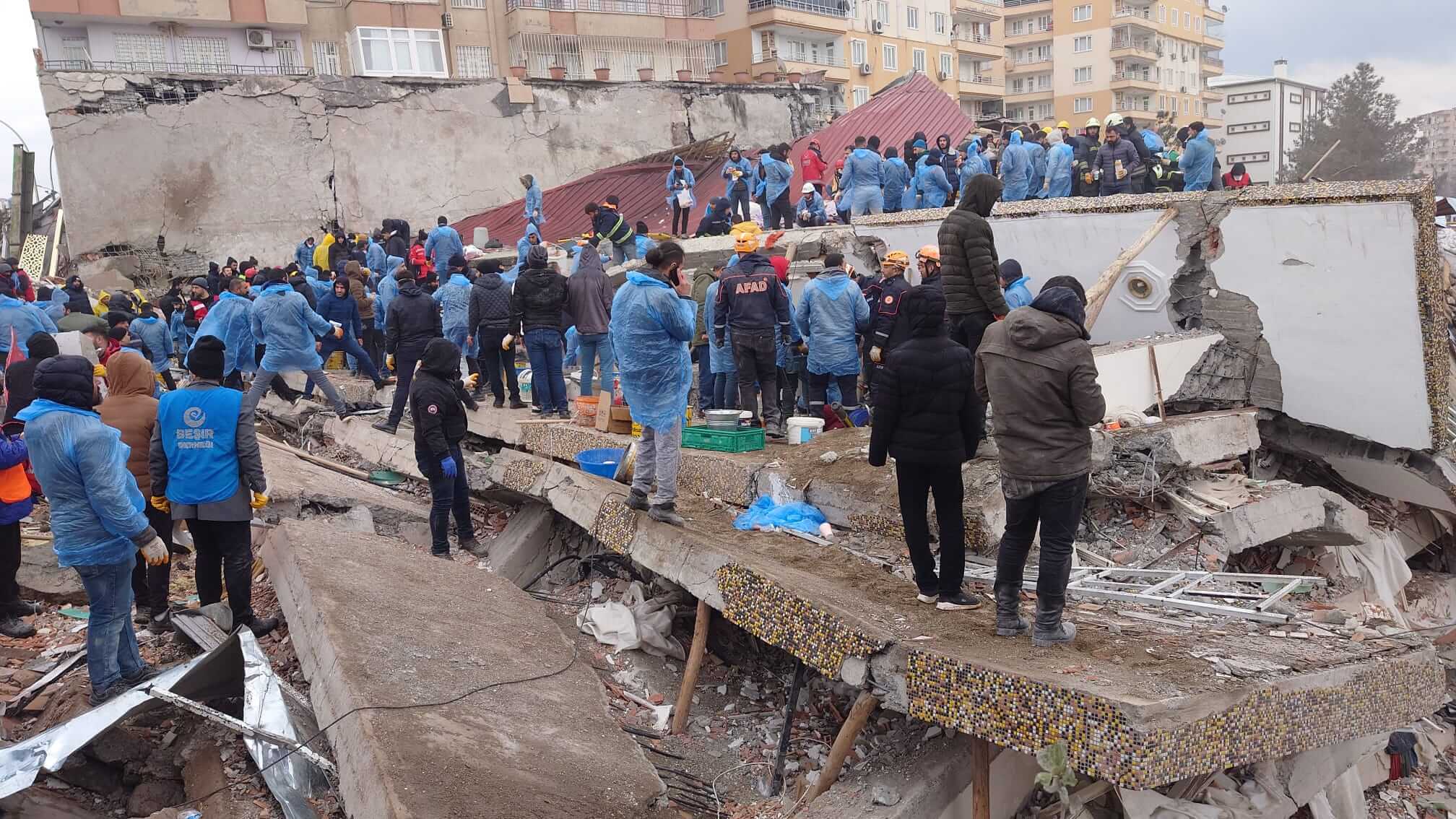 people standing around collapsed building