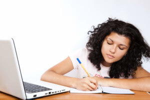 woman with notepad and laptop looking studious
