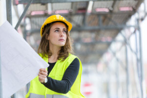 woman on construction site holding plans