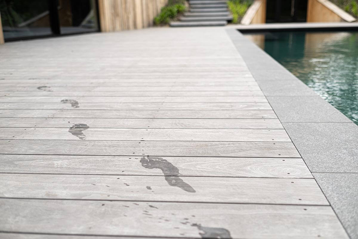 Footstep marks lead toward an unknown destination beside a pool