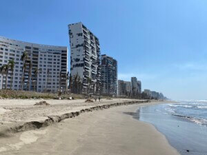 Image of beach shore with tall buildings damaged after a hurricane.