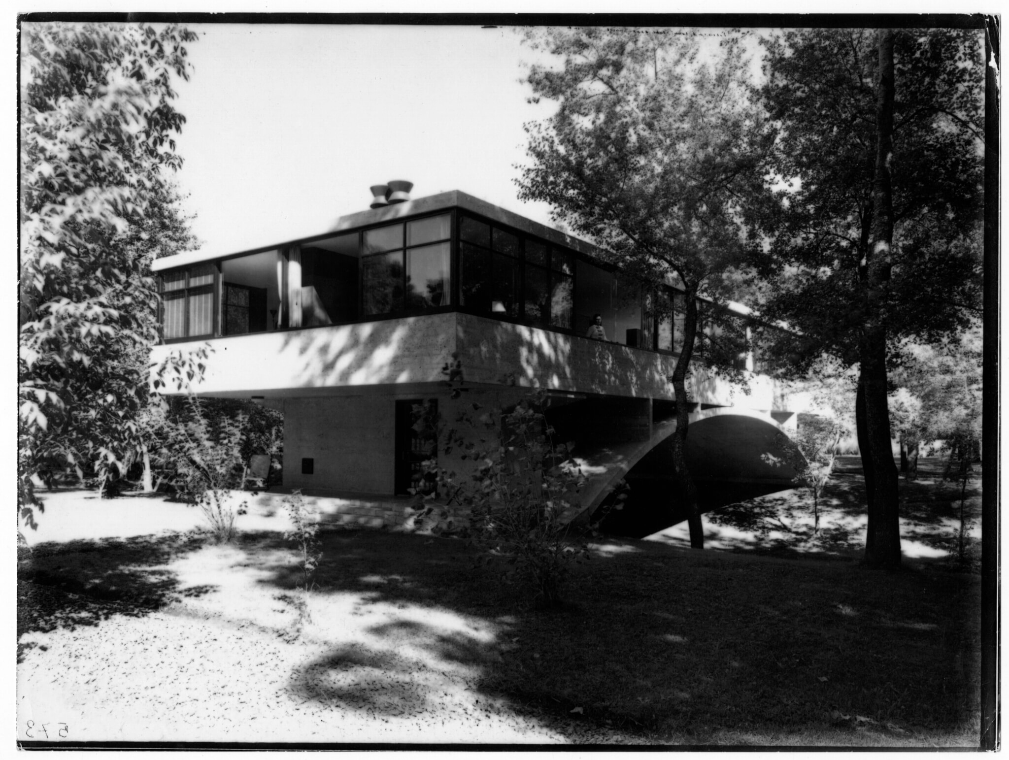 Black and white image of a house over a stream.