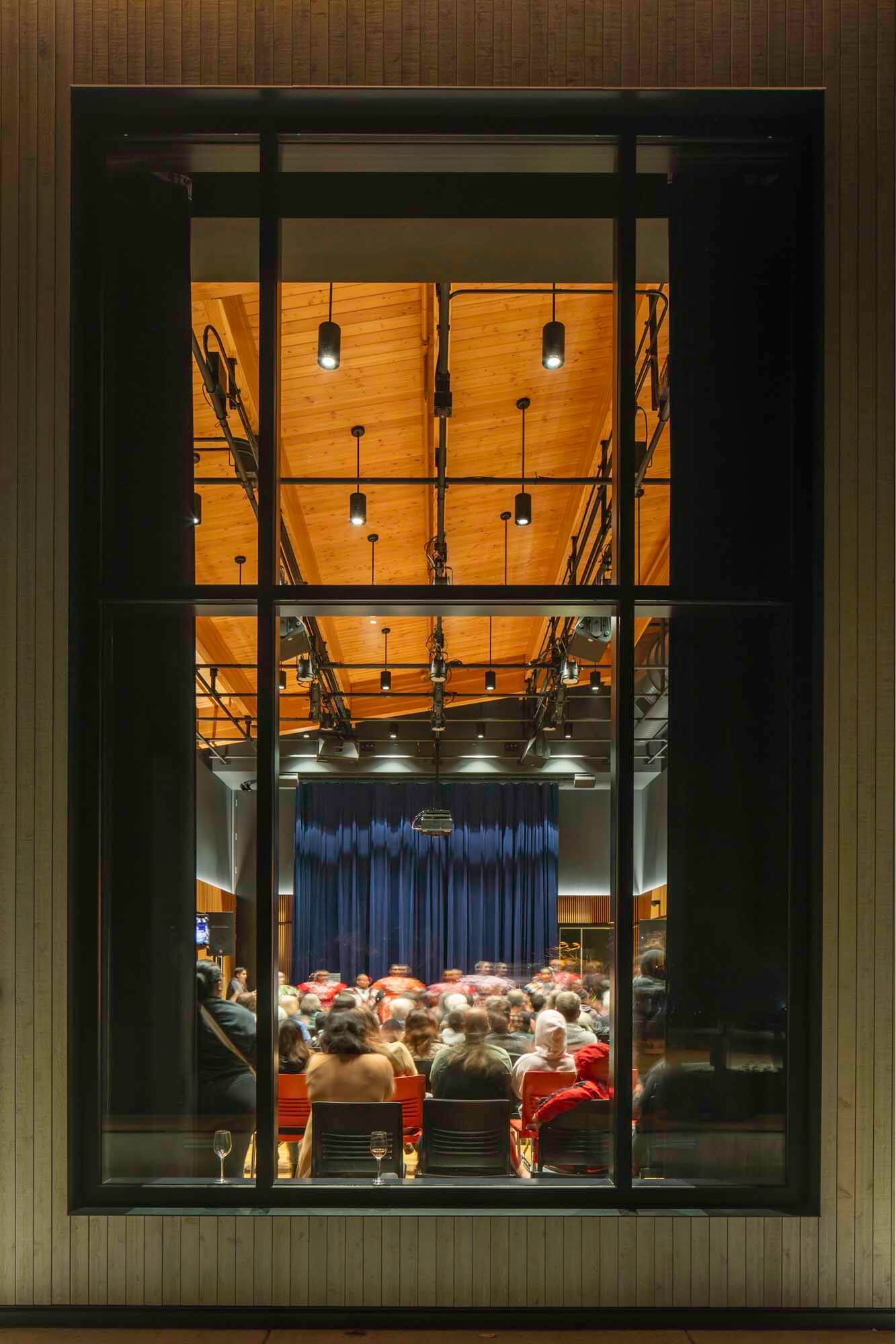 A view from the outside into a performing venue through a window.