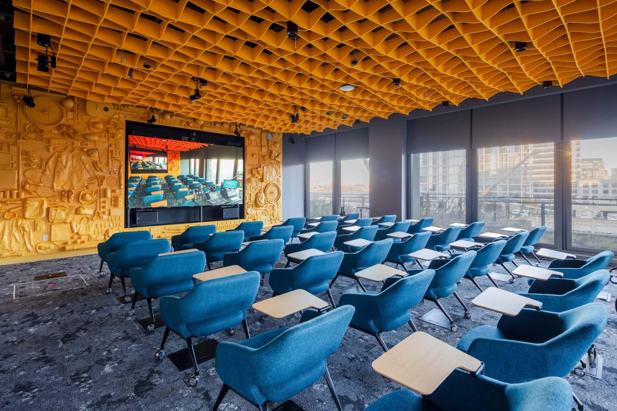 a meeting space with yellow walls and blue chairs